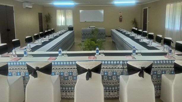 A conference room with long tables, chairs, and a projector screen. - Nakelo Treasure Island Resort & Spa (Treasure Island)