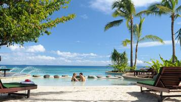 Aan een privéstrand, wit zand, ligstoelen, parasols