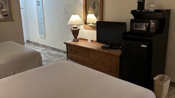 Une chambre d’hôtel avec deux lits, une commode en bois, une télévision, une machine à café et une poubelle.