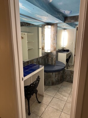 Un baño con piso de azulejos, lavamanos, espejo y tocador con encimera azul.