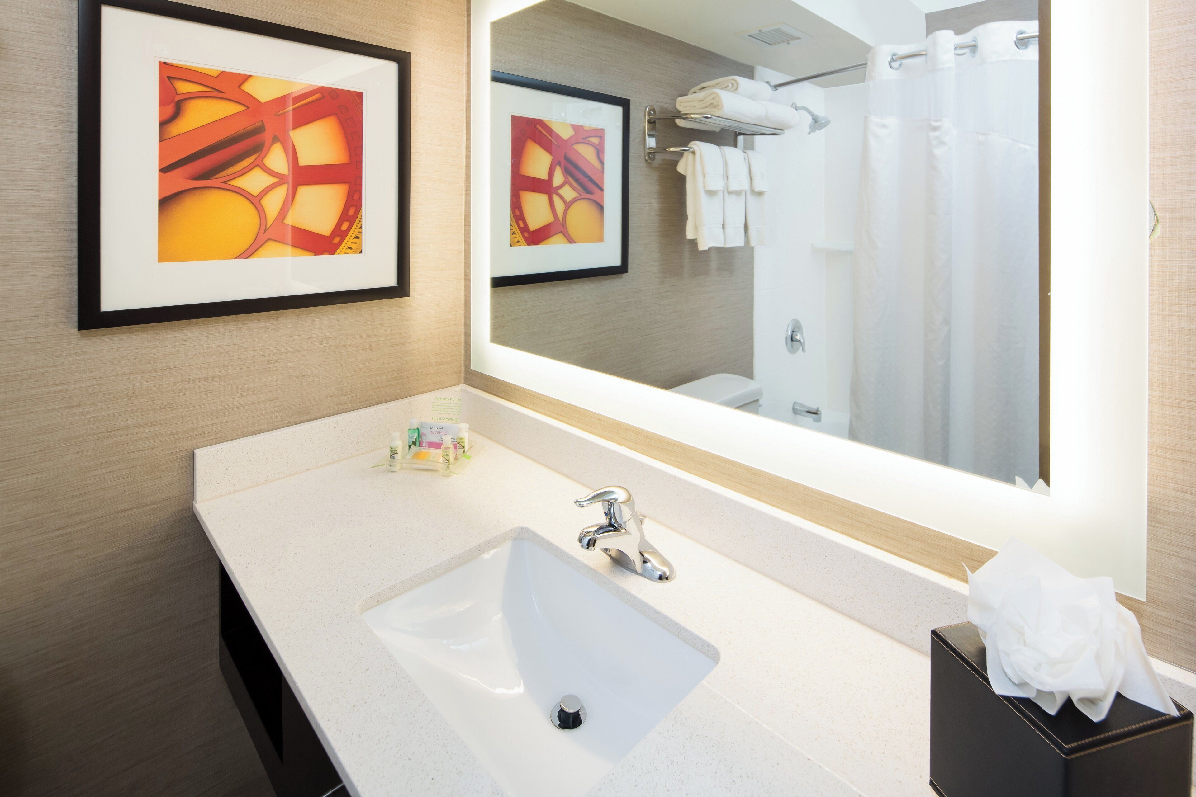 Un baño moderno con un espejo grande, un lavamanos y un perchero para toallas.