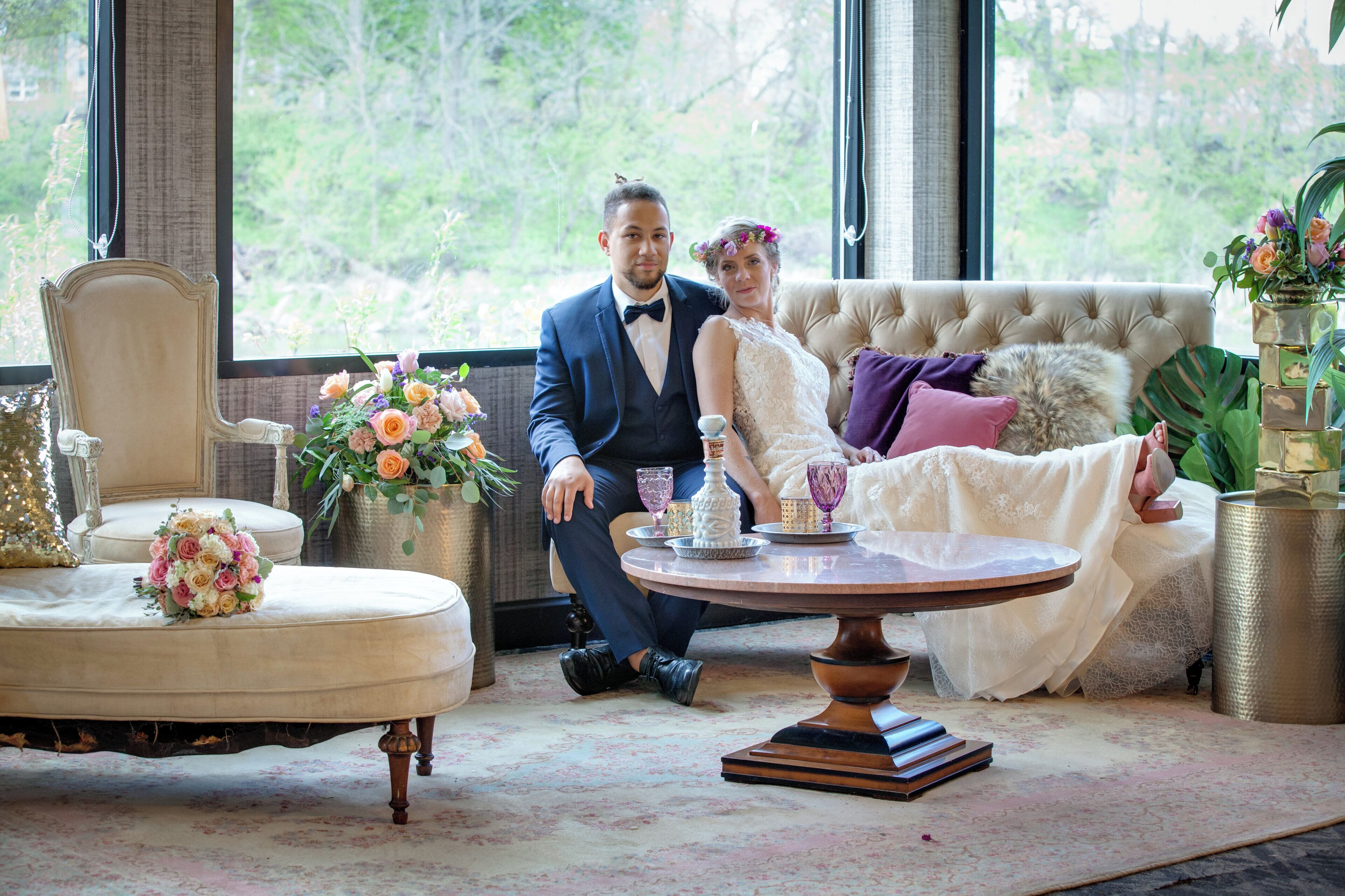 A room with a large window, a sofa, a round table, and a decorative vase.