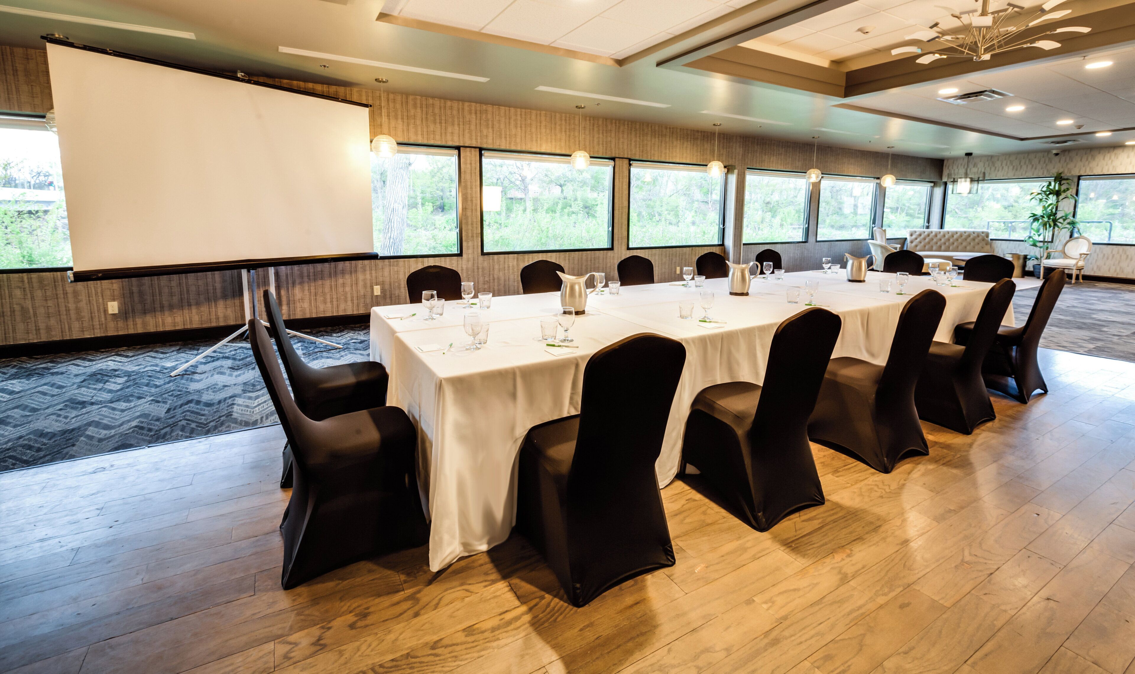 Un salón de conferencias con una mesa larga, sillas y una pantalla para proyector.