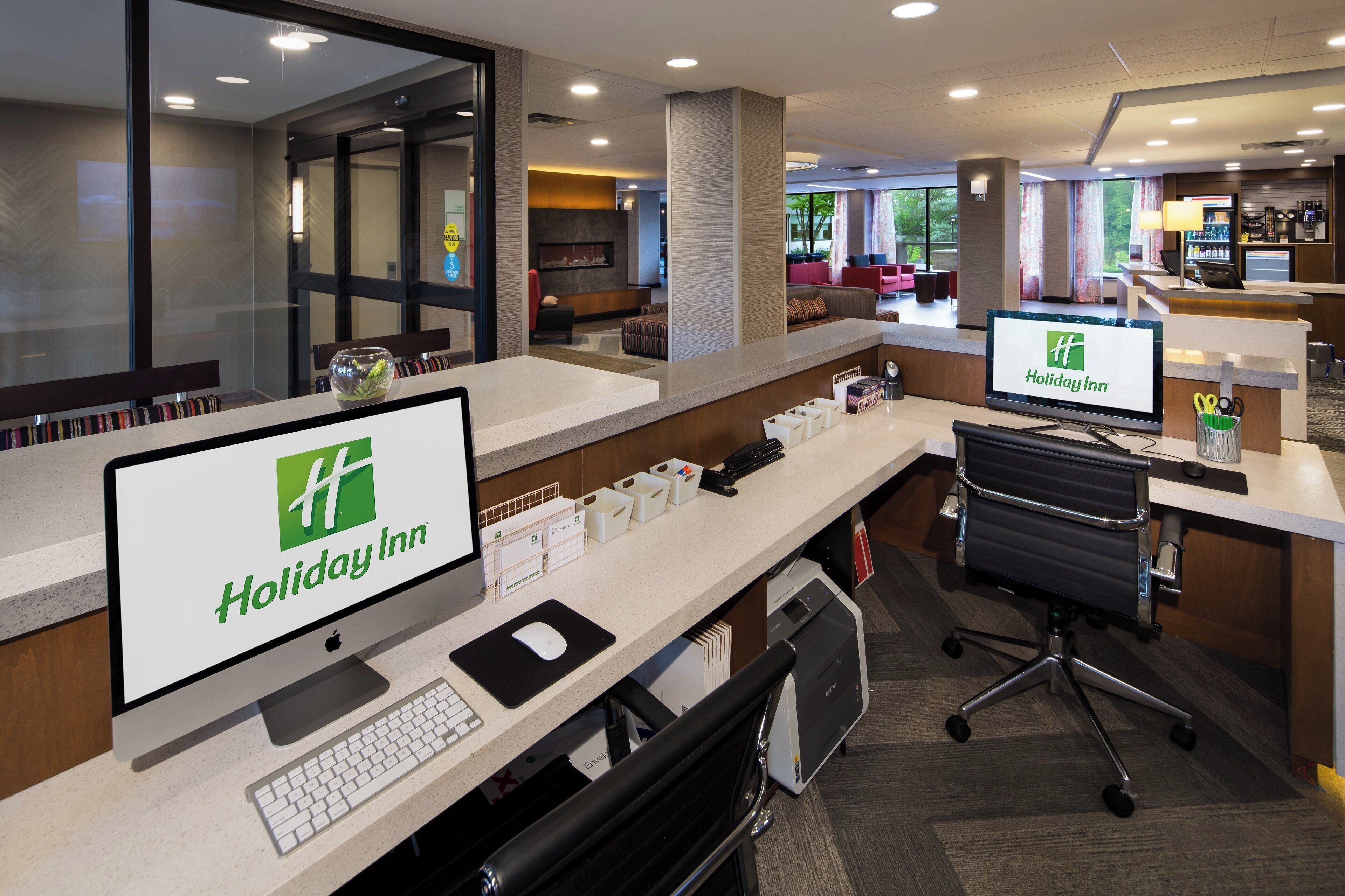 Mostrador de recepción de Holiday Inn con computadora, teclado y silla de oficina.
