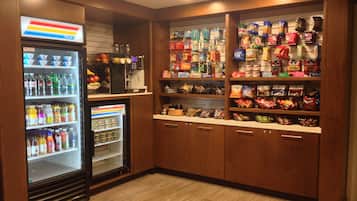 Zona de venta automática con aperitivos y bebidas, que incluye varios productos y un dispensador de bebidas.