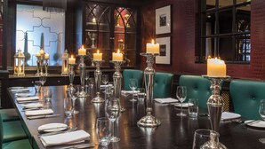 Un restaurante con una larga mesa dispuesta para comer, velas y cristalería.
