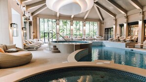 Una amplia piscina interior con zonas de descanso y un jacuzzi.