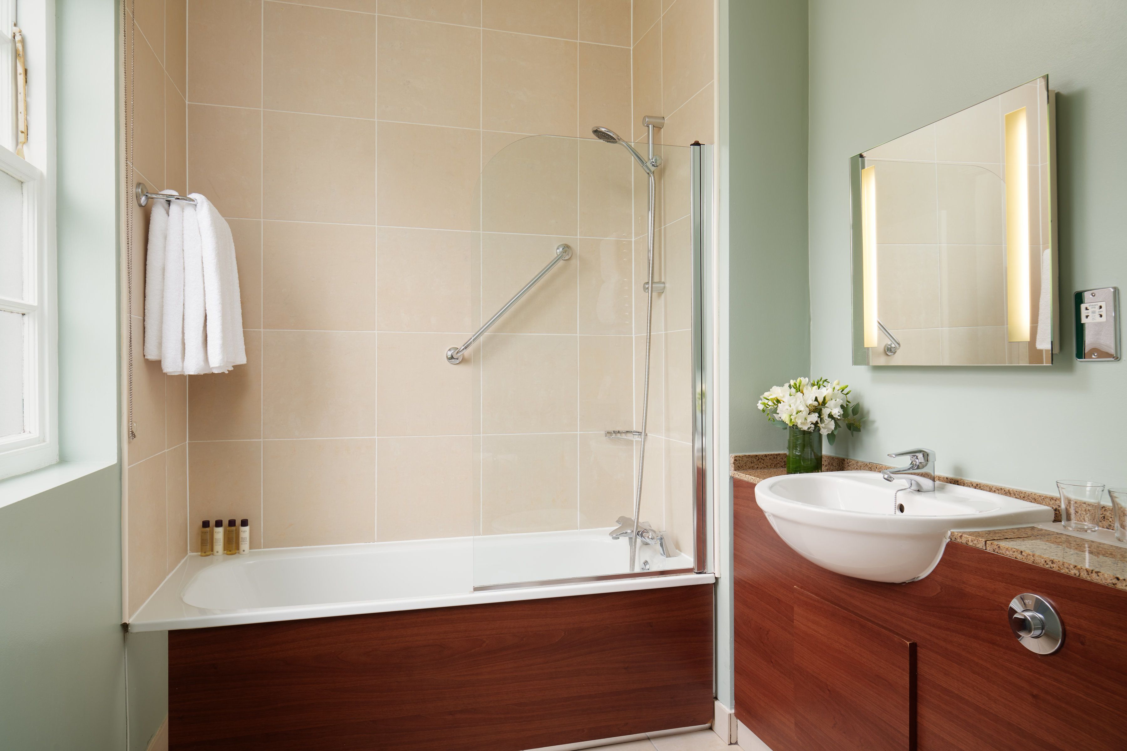 Un baño con bañera, lavabo y espejo.