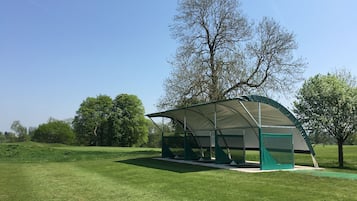 Relax in a serene outdoor pavilion surrounded by lush greenery and mature trees.