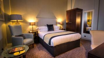 Ein Hotelzimmer mit einem großen Bett, einem Sessel, einem kleinen Tisch und einem Kleiderschrank.