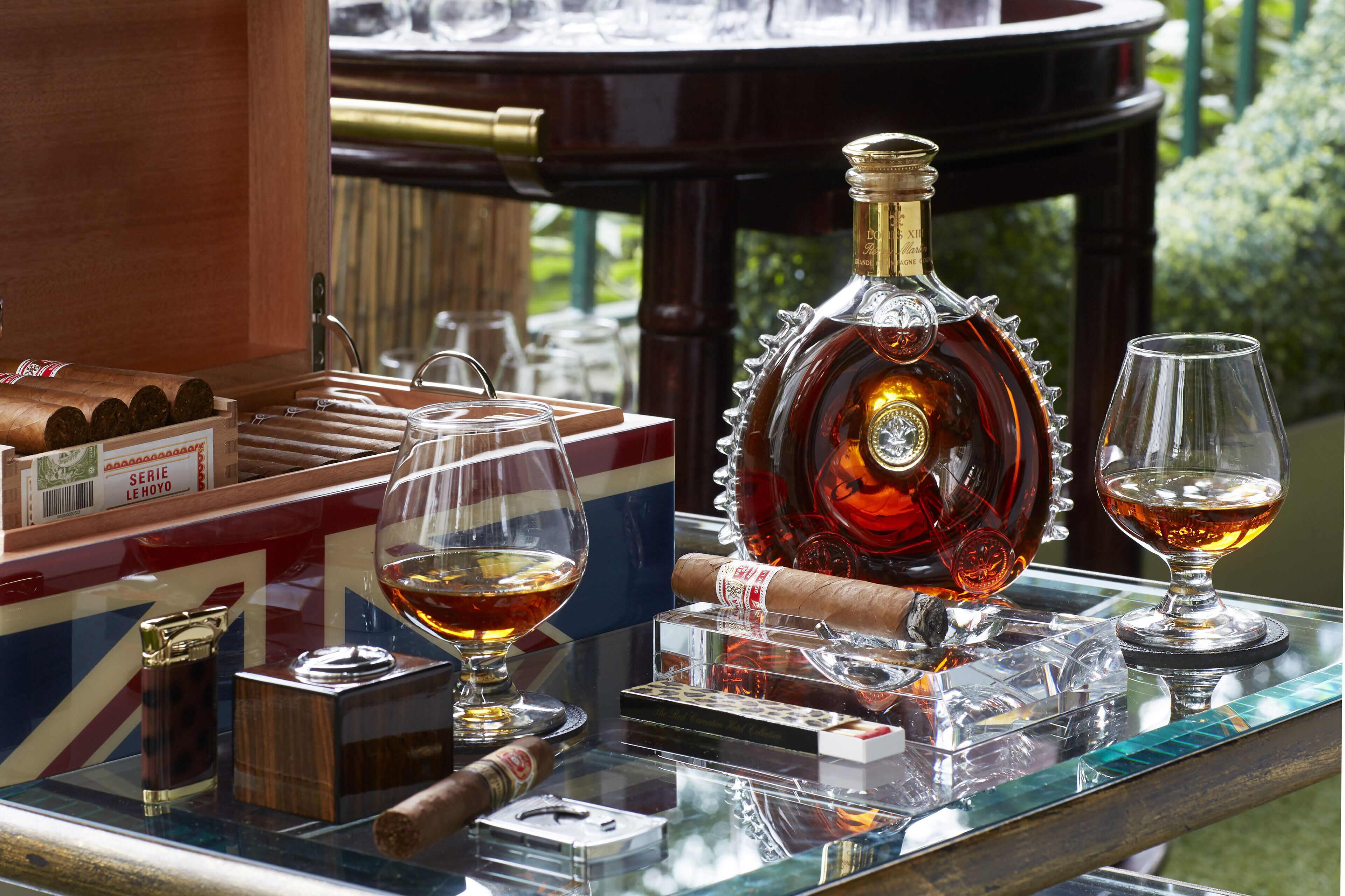 Una vitrina de vidrio con cigarros, una botella de licor y dos vasos.