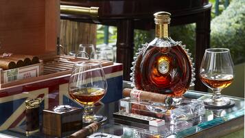 Una vitrina de vidrio con cigarros, una botella de licor y dos vasos.