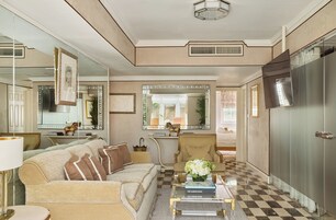 A well-lit living room with a checkered floor, a sofa, a coffee table with books, and a large mirror.