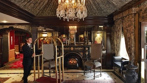 Un lobby imponente con candelabro, chimenea y decoración elaborada.