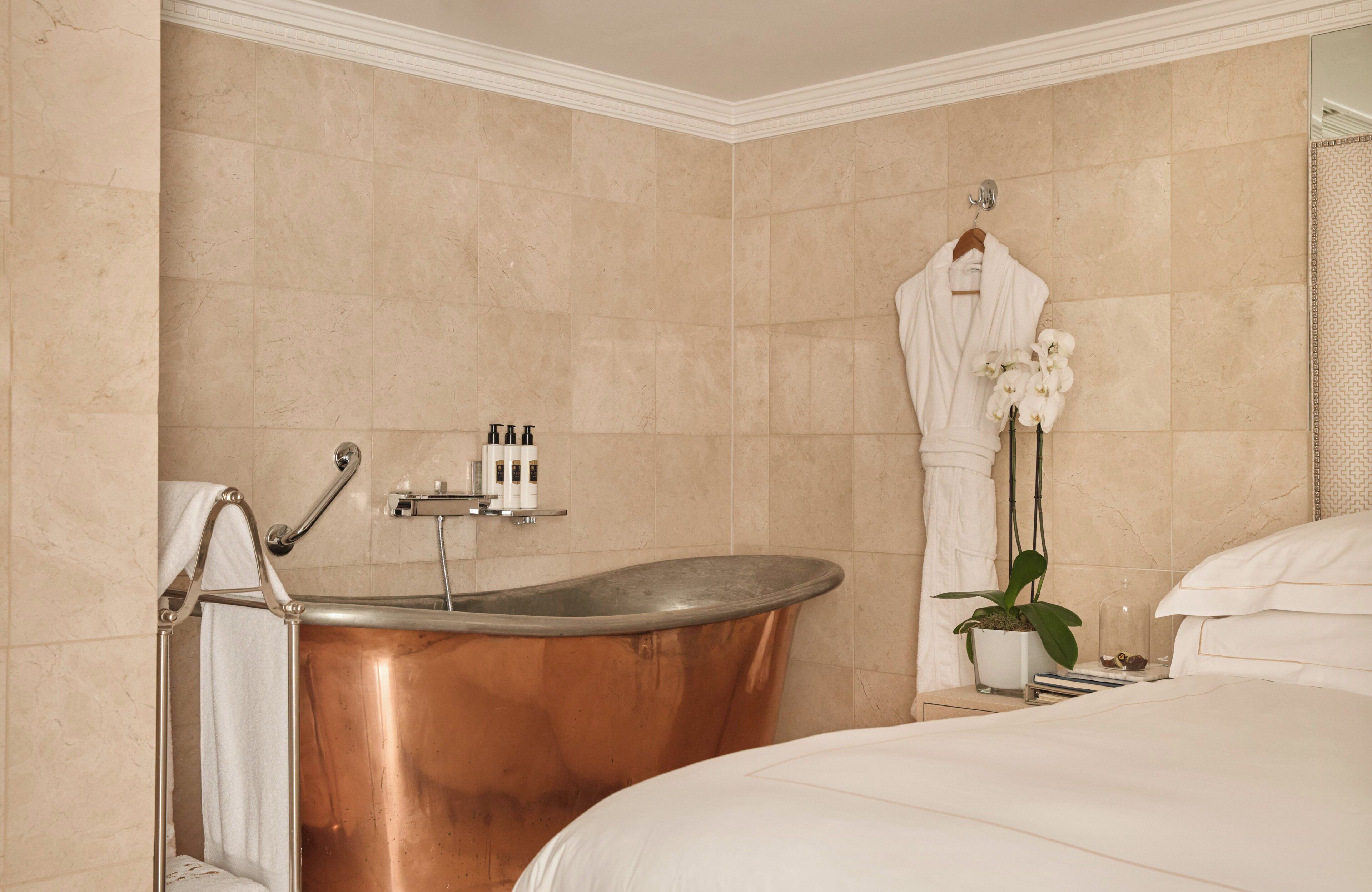 A modern bathroom with a freestanding bathtub, a towel rack, and a potted orchid.