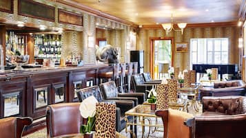 Uma área de bar com diversas opções de assento, incluindo poltronas de couro e mesas, além de um balcão com garrafas e copos.