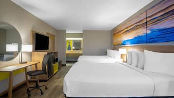 Ein Hotelzimmer mit einem großen Bett, einem Schreibtisch mit Stuhl, einem Fernseher und einem Bild an der Wand.