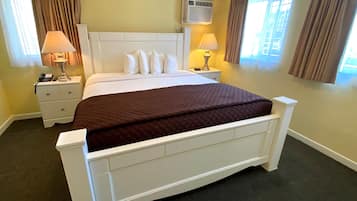 Ein Hotelzimmer mit einem großen Bett, zwei Nachttischen mit Lampen, einem weißen Kopfteil und beige gestrichenen Wänden.