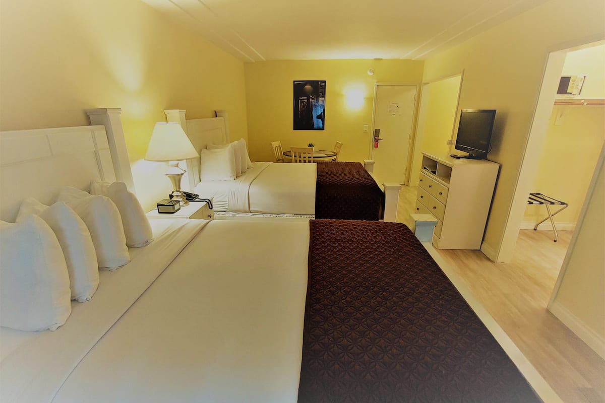 A hotel room with a bed, a desk, a chair, a television, and a small cabinet.
