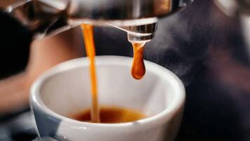 A close-up of a coffee machine dispensing espresso into a cup.