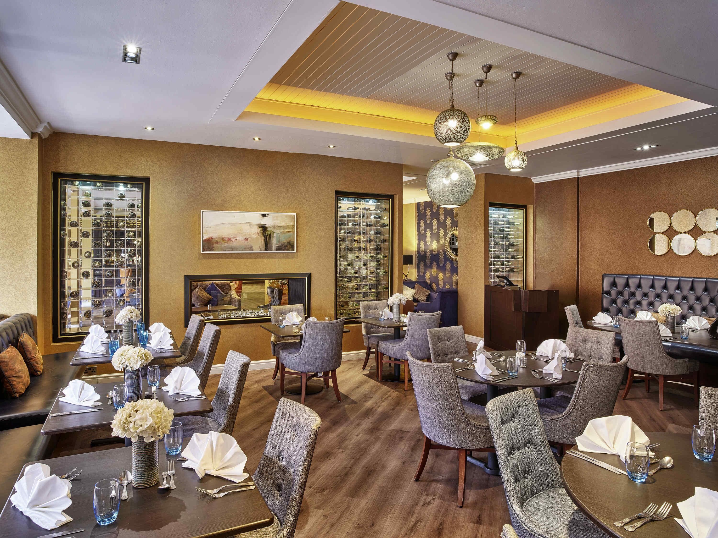 A restaurant with multiple dining tables, chairs, and a bar area.