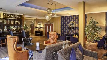 A hotel lobby with a bar, seating area, and a 'Walling Suite' sign.