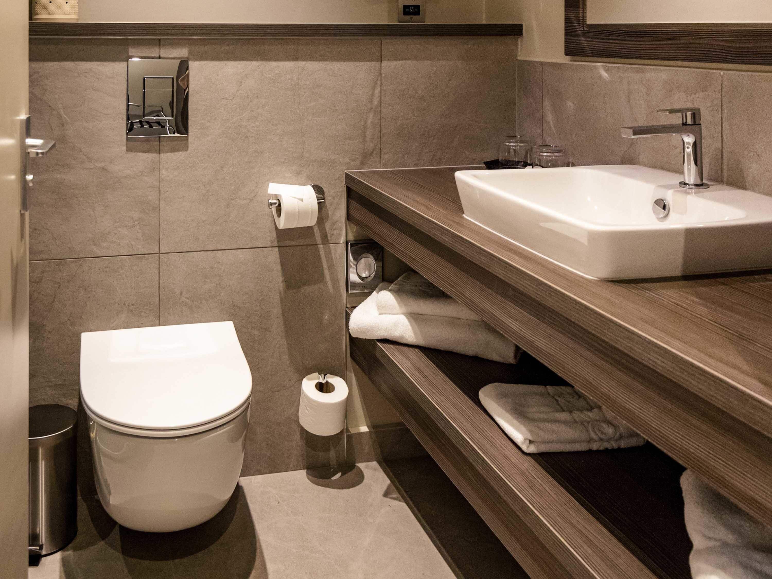 A modern bathroom with a toilet, sink, and towel rack.