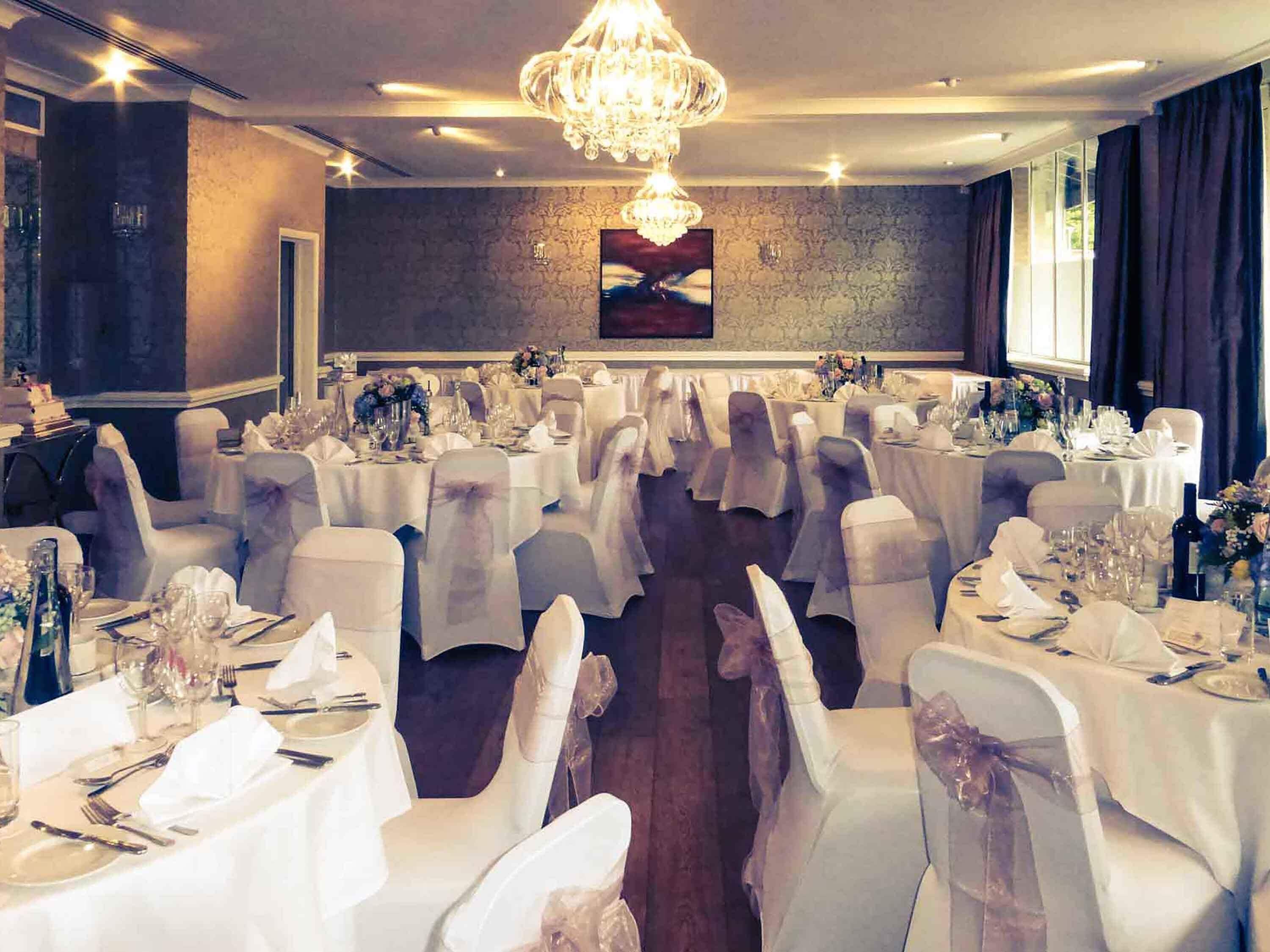 A banquet hall with round tables, white tablecloths, and chairs with white sashes.