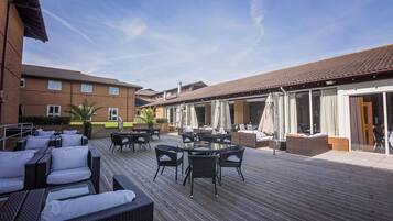Un espace extérieur aménagé en terrasse, avec des meubles en osier et une plateforme en bois.