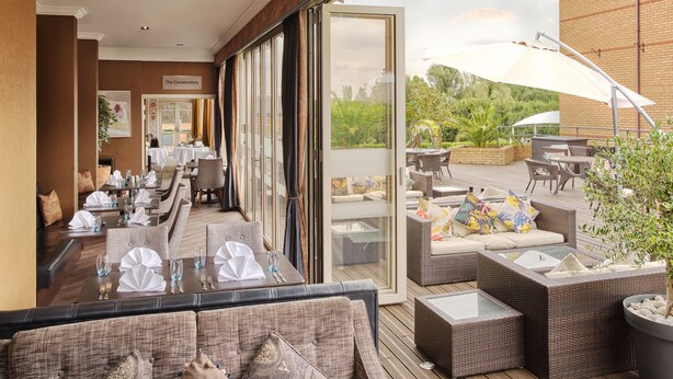 A restaurant with outdoor seating, a conservatory, and a view of the garden. - Mercure Milton Keynes (Milton Keynes)
