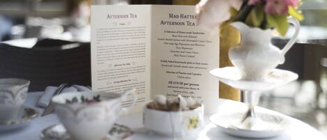 A menu with afternoon tea options and a tea service setup on a table.
