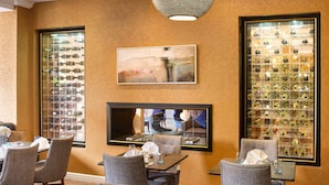 A dining area with a large table, multiple chairs, a television, and wine racks on the walls. - Mercure Milton Keynes (Milton Keynes)