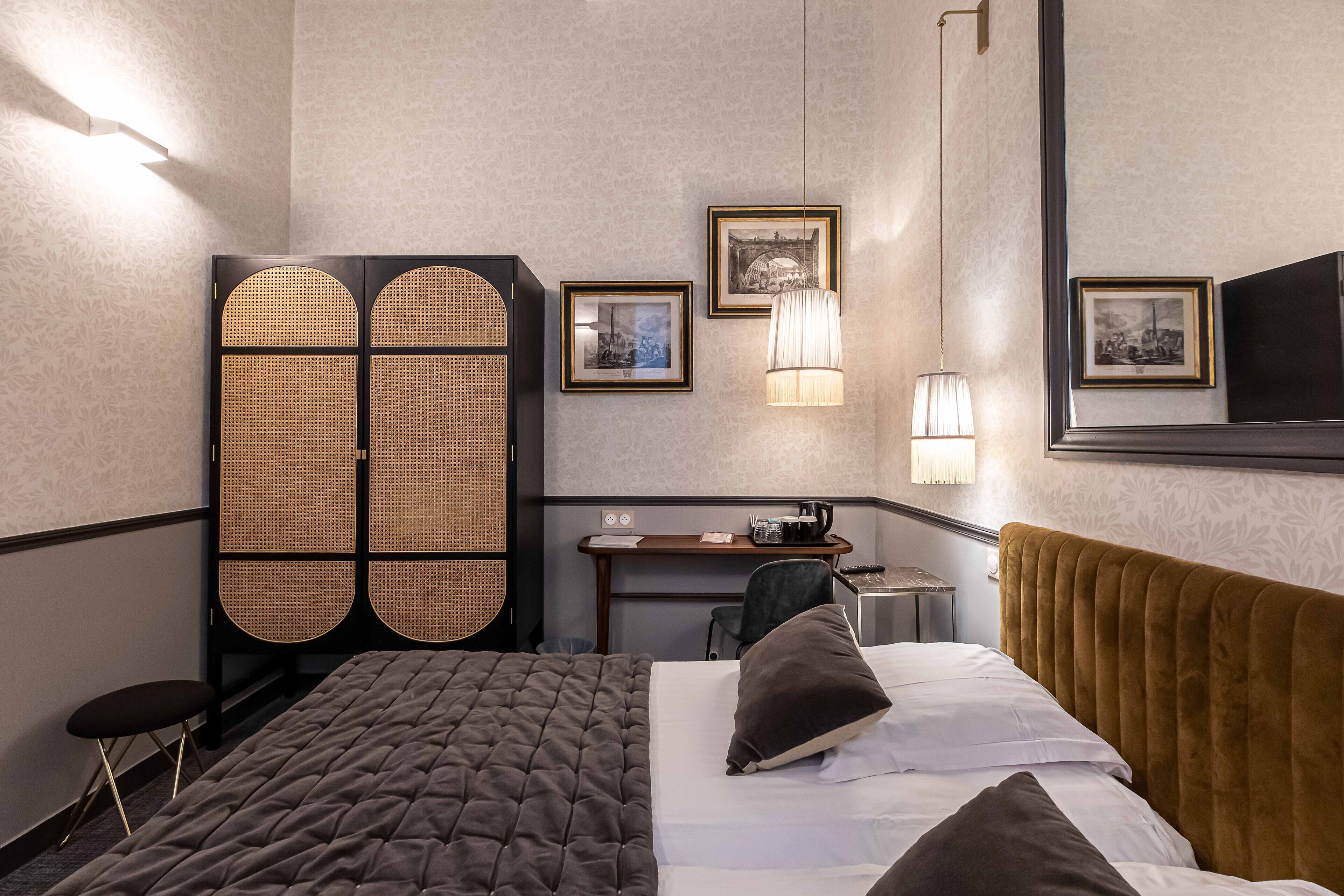 A hotel room with a bed, a desk, a chair, and a wardrobe.