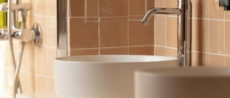 A bathroom with a white sink, a chrome faucet, and a tiled wall.