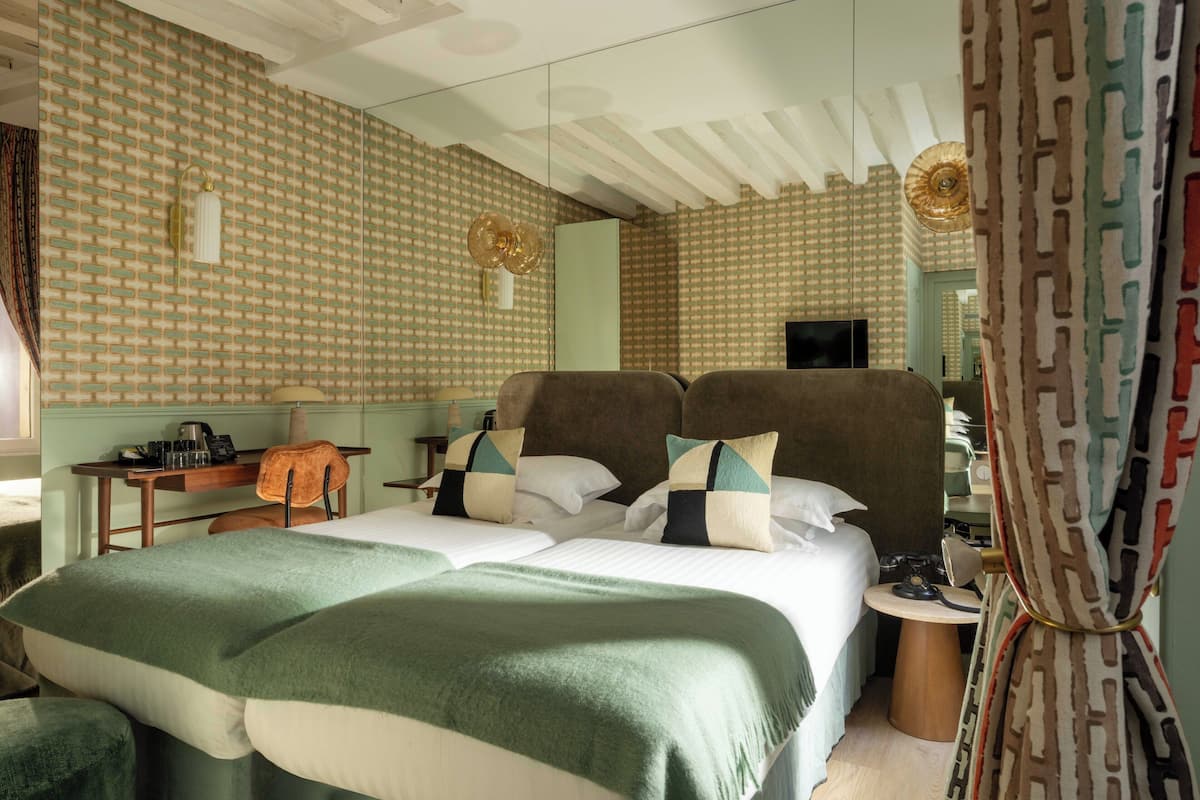 A hotel room with a large bed, a desk with a chair, a small table, and a television.