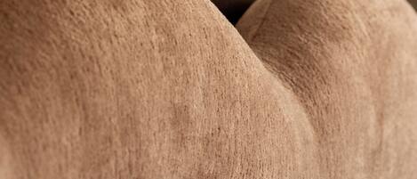 A close-up of a textured, upholstered headboard with a smooth, rounded design.