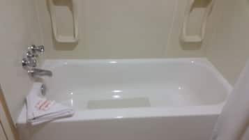 A white bathtub with a single faucet and a small shelf above it.