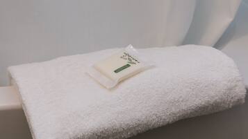 A neatly folded white towel on a white surface with a small package labeled "Eco-Loc" on top.