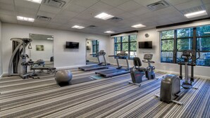 Ein Fitnessstudio mit Laufbändern, Crosstrainern und Übungsbällen.