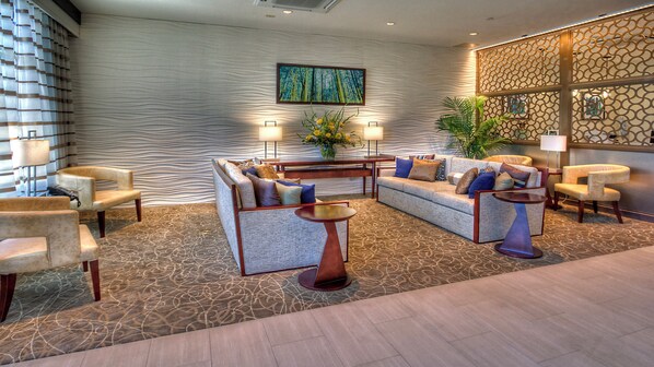 A lobby with a sofa set, armchairs, a coffee table, and a decorative wall with a painting. - Holiday Inn Hotel & Suites Tupelo North by IHG (Tupelo)