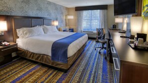 A hotel room with a large bed, a desk, a TV, and a window with curtains. - Holiday Inn Hotel & Suites Tupelo North by IHG (Tupelo)