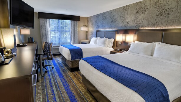 A hotel room with two beds, a desk, a chair, a TV, and a window with curtains. - Holiday Inn Hotel & Suites Tupelo North by IHG (Tupelo)