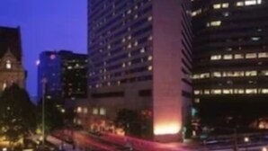 A cityscape at dusk with modern buildings, a busy street, and a parking lot. - The Plaza Hotel Columbus at Capitol Square (Columbus)