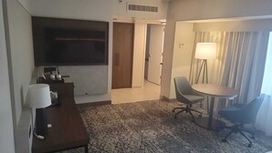 A hotel room with a desk, chair, table, lamp, and a large window with curtains. - The Plaza Hotel Columbus at Capitol Square (Columbus)