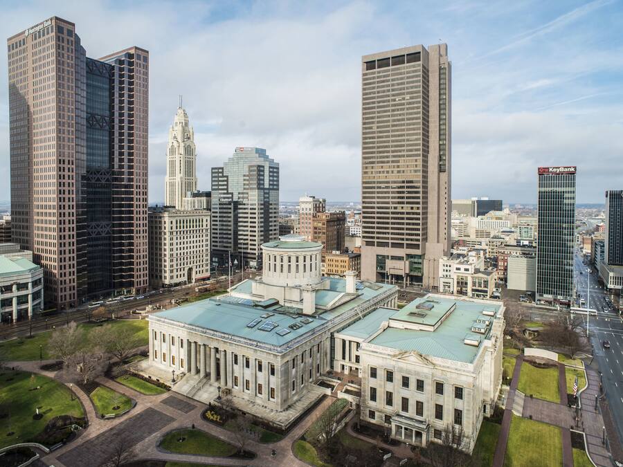 Paisagem urbana com arranha-céus modernos, edifícios históricos e um grande edifício central com cúpula.