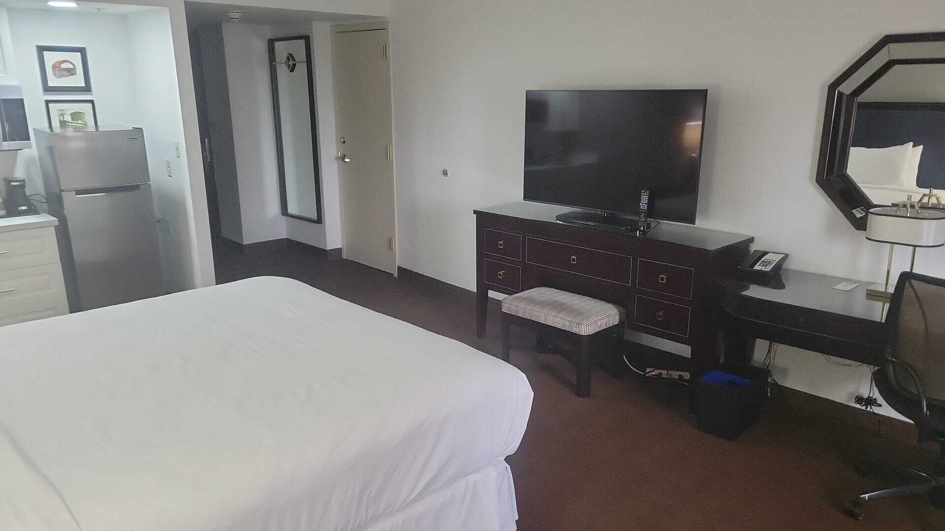A hotel room with a bed, a desk with a computer, a television, and a mirror.