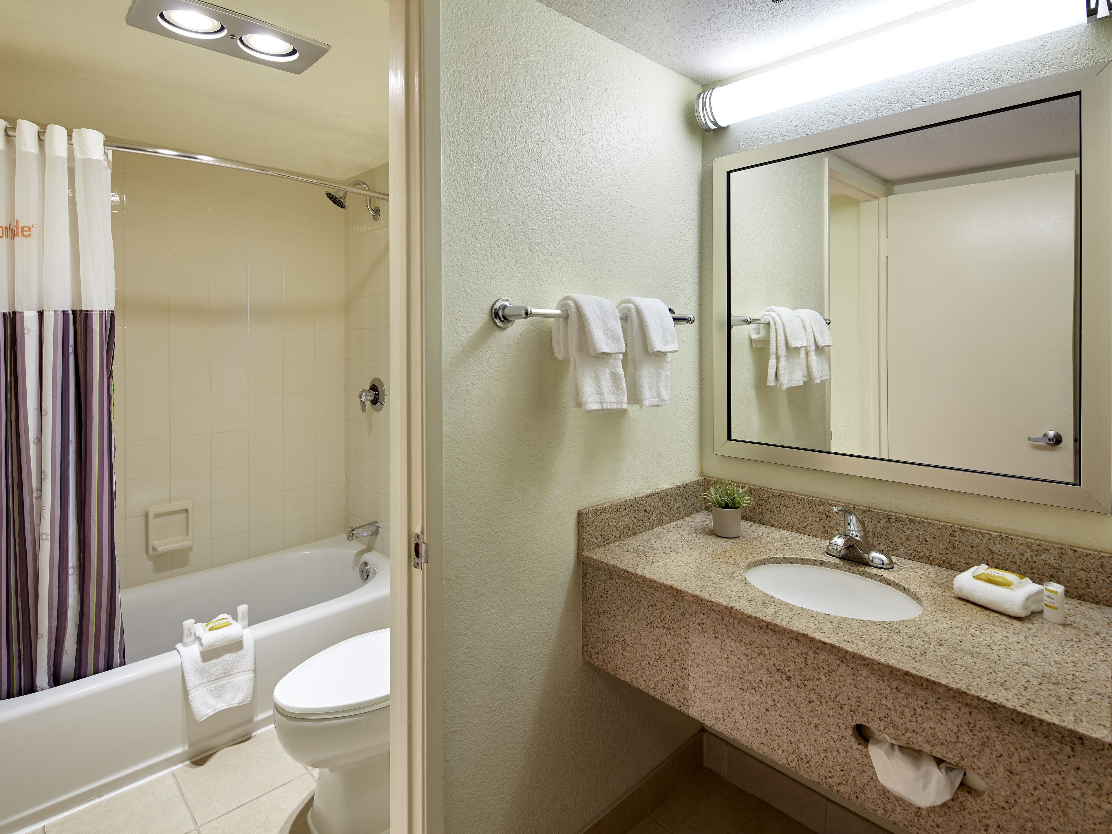A bathroom with a bathtub, toilet, sink, and a large mirror.