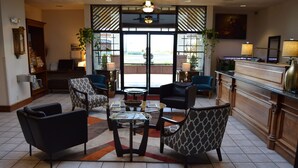 A lobby with a reception desk, seating area with patterned chairs, a coffee table, and a view through the glass doors. - Ramada by Wyndham Arcata (Arcata)