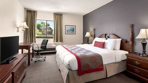 A hotel room with a bed, desk, chair, TV, and two lamps. - Ramada by Wyndham Arcata (Arcata)
