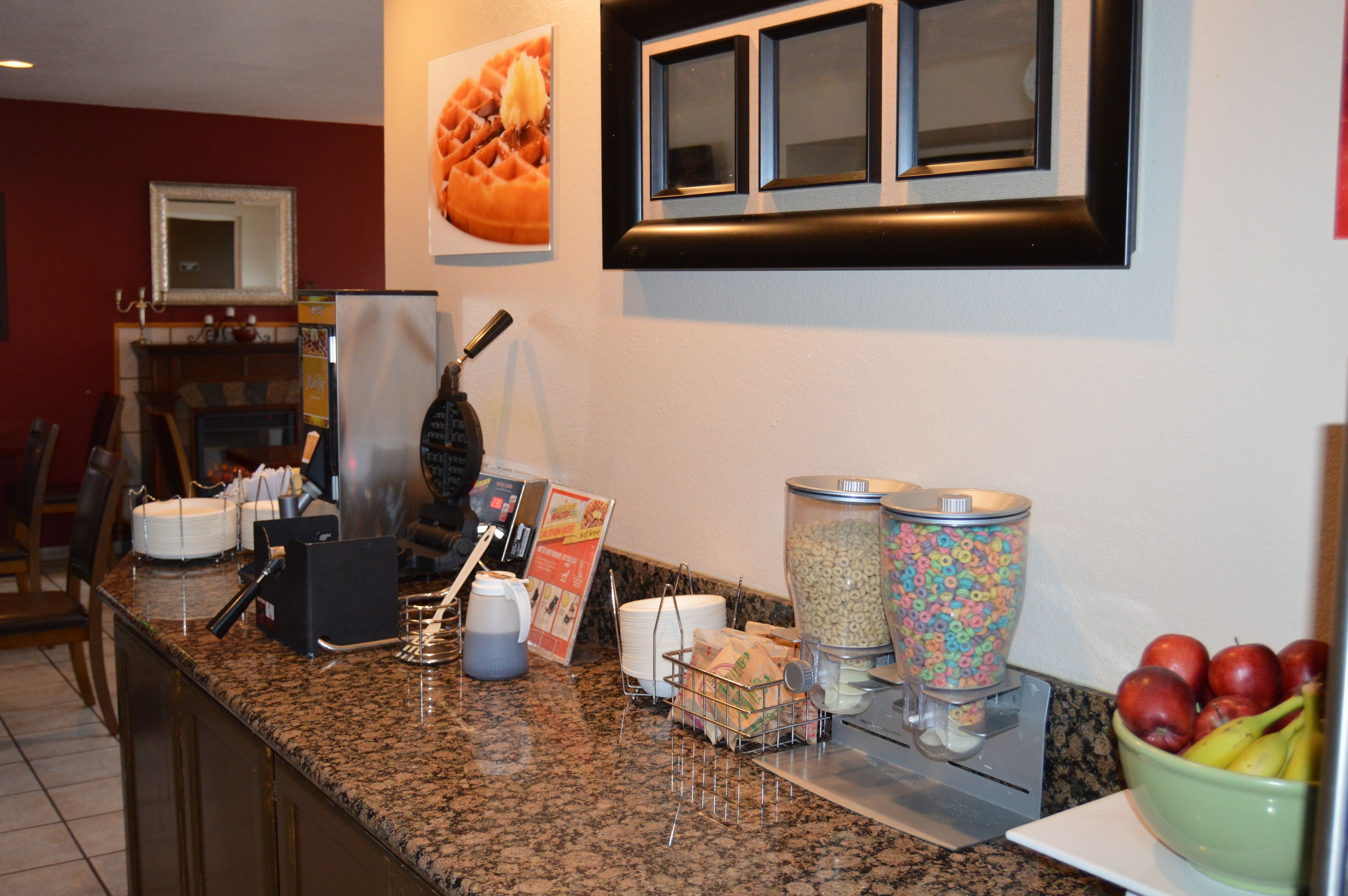 A breakfast bar with a waffle, cereal, and fruit.
